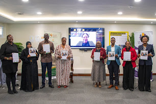 Launch participants standing together and holding copies of the report