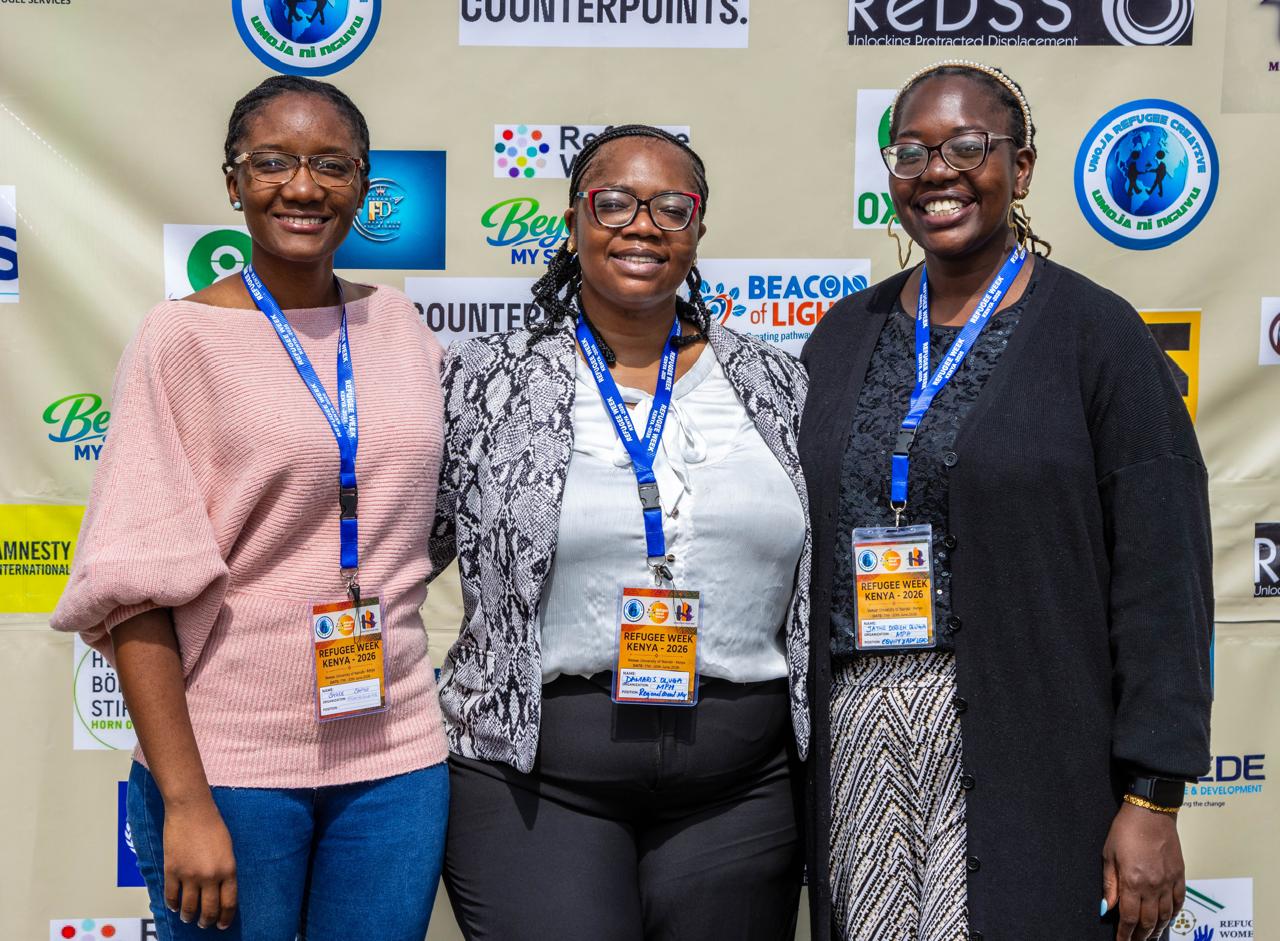Three members of the Migration Pulse Hub team smiling together at Refugee Week Kenya 2026